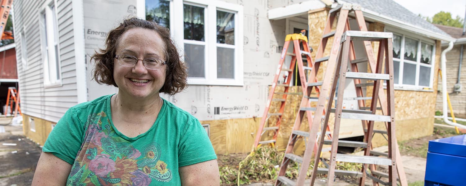 Woman in front of home in process of repairs